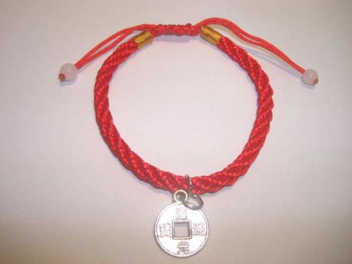 Red thread bracelet with a rare coin to attract good luck